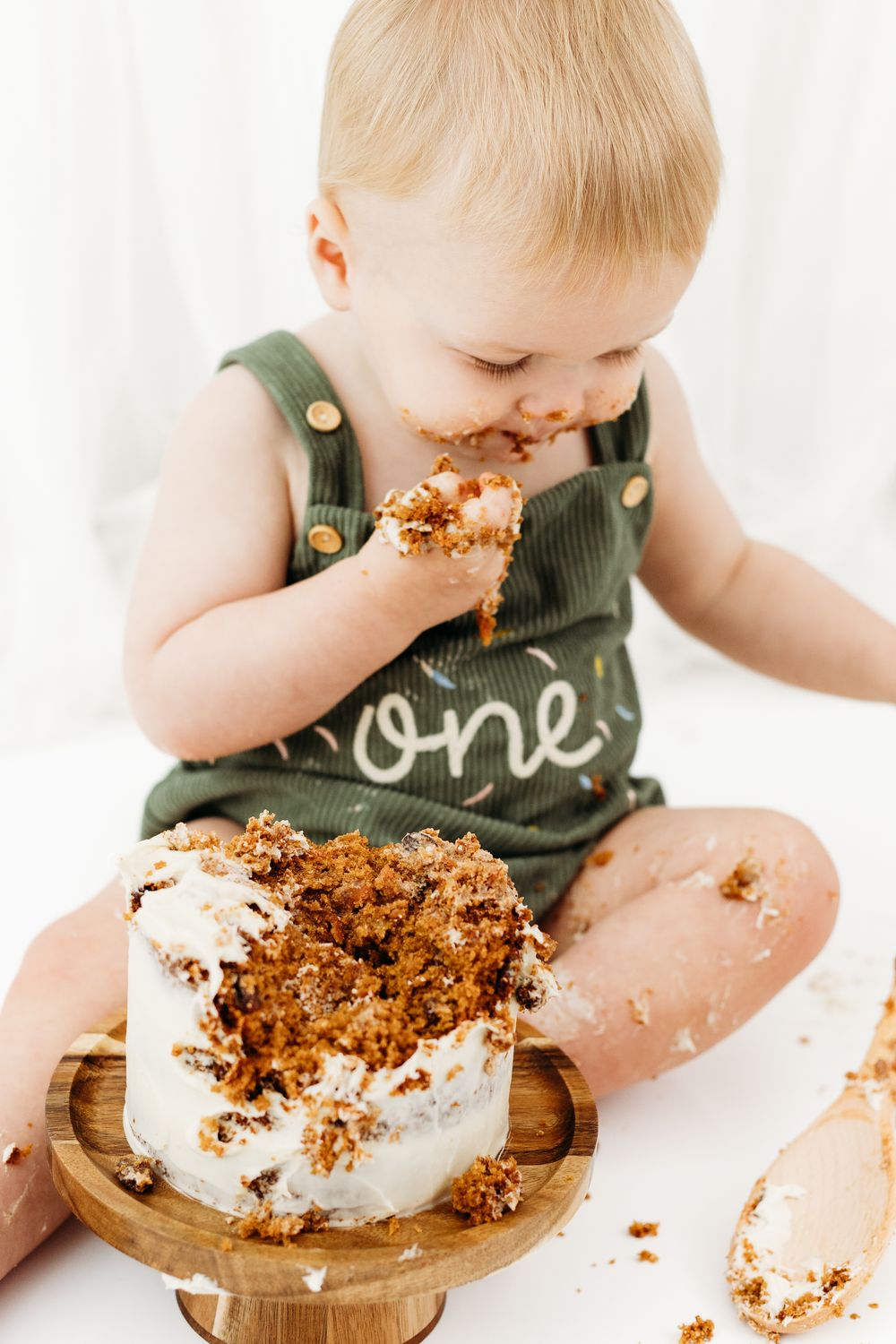 Baby celebrating first birthday in cake smash session, natural and joyful portraits captured in Nottingham studio.