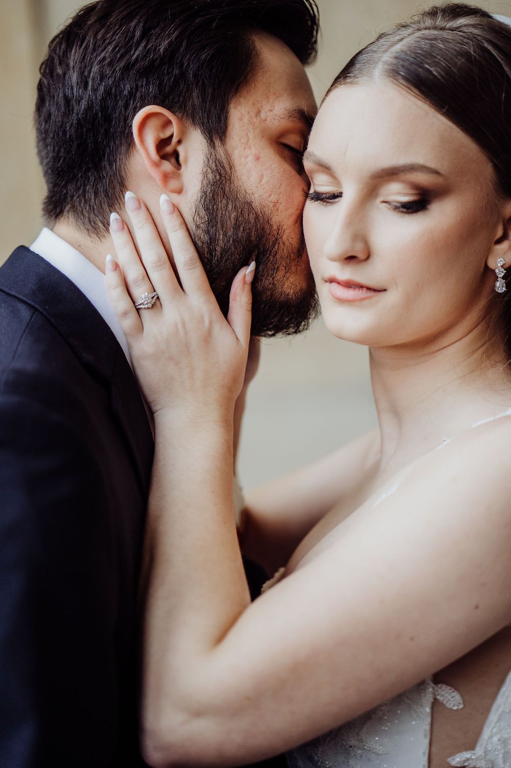 Romantic wedding couple sharing an intimate moment, groom whispering to bride wearing diamond ring and elegant earrings.