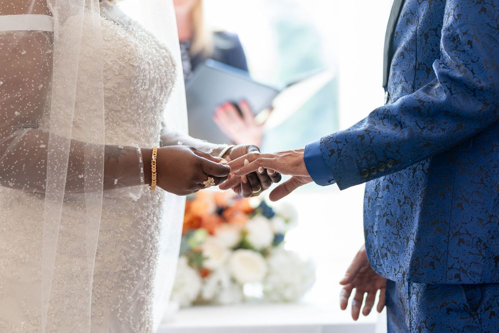 Close-up of couple exchanging wedding rings during ceremony.