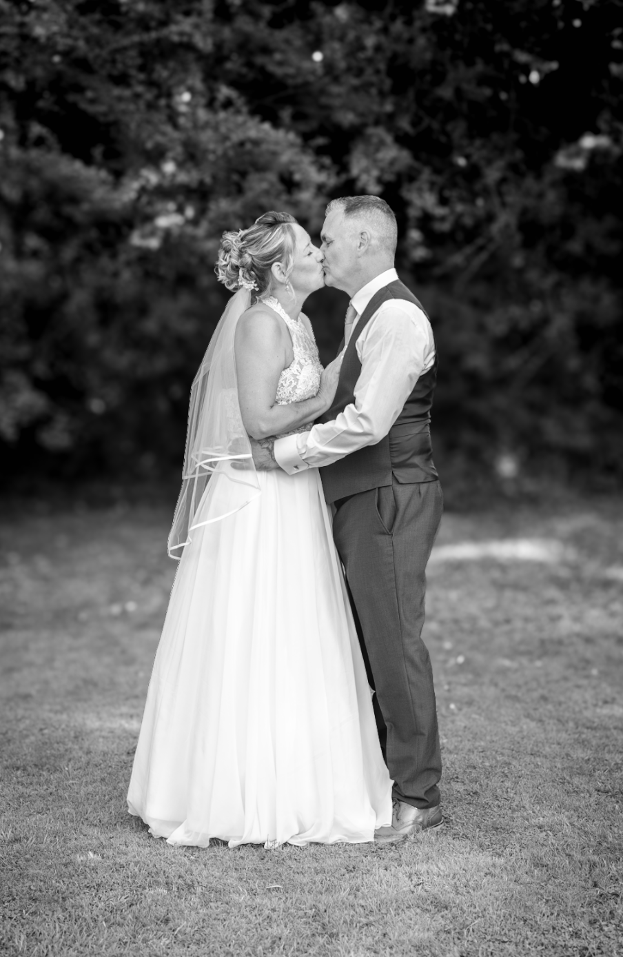 Wedding couple embracing outdoors in black and white portrait.