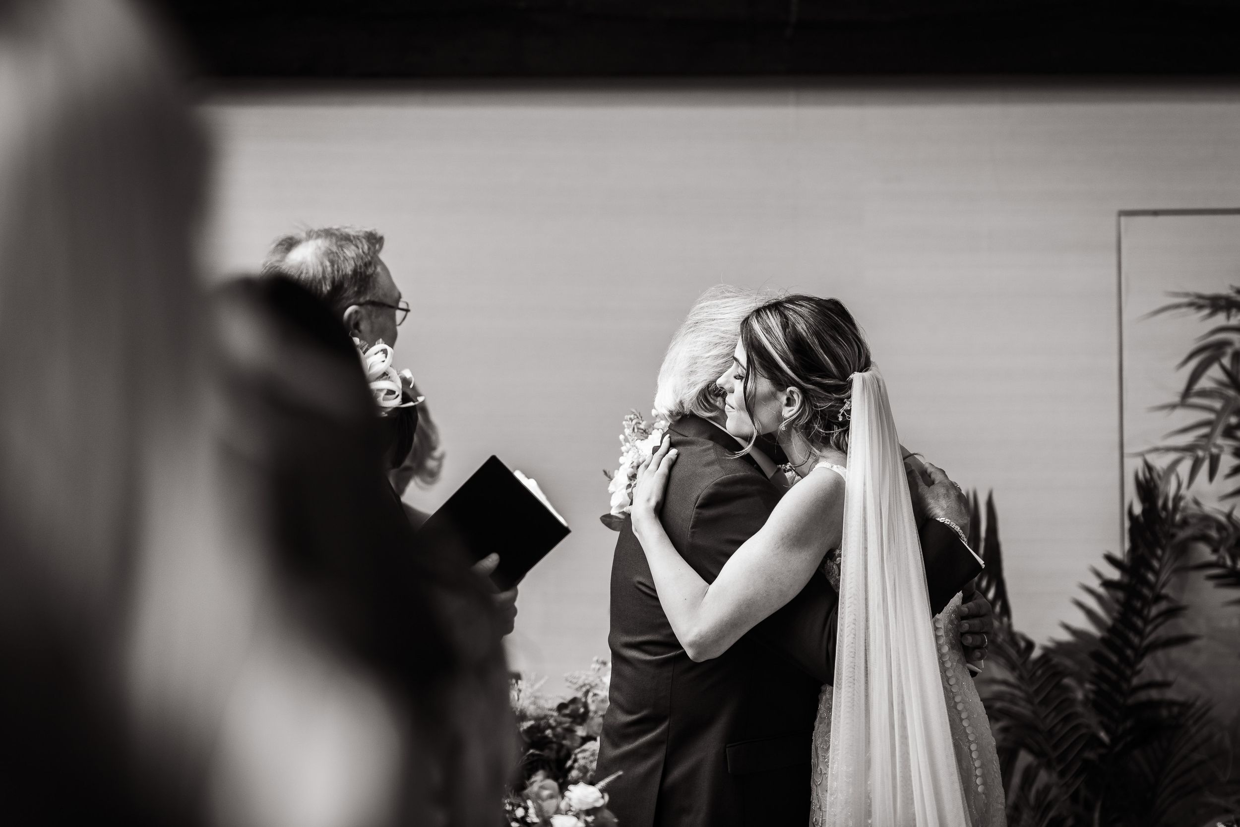 Black and white photograph capturing emotional ceremony moment during indoor wedding.