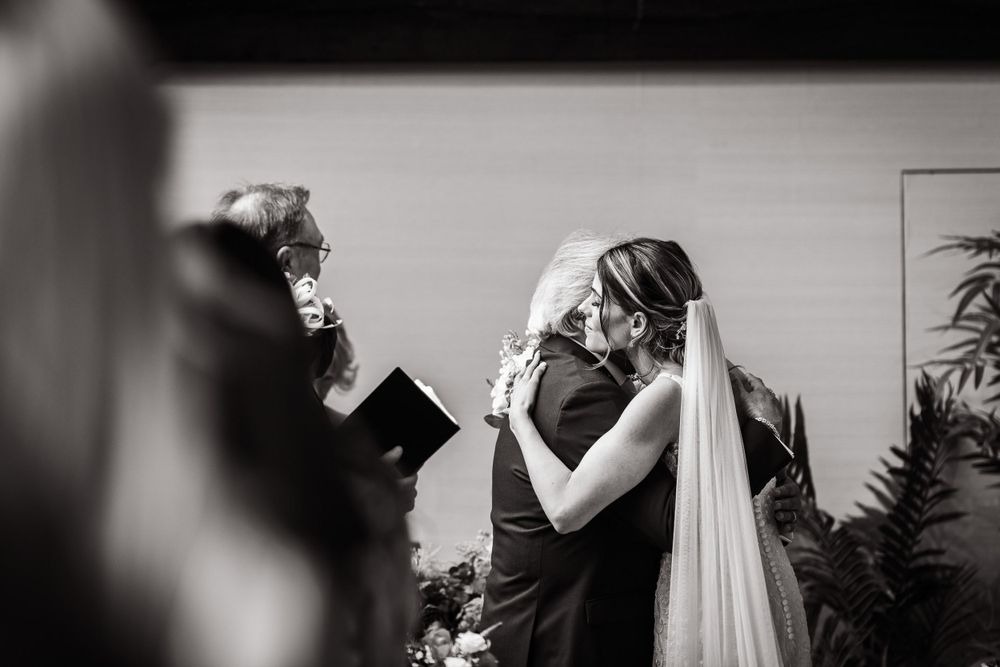 Black and white photograph capturing emotional ceremony moment during indoor wedding.