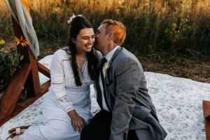 Romantic moment between couple on white blanket during golden hour in field.