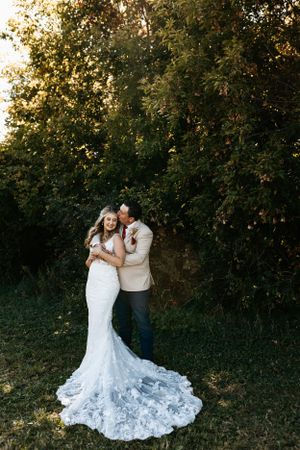 A romantic moment captured between newlyweds outdoors with a stunning lace wedding dress train.
