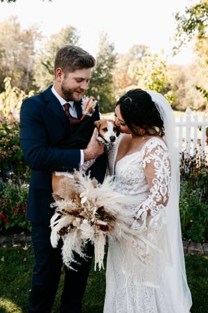 A couple shares a joyful moment with their small dog during their wedding celebration.