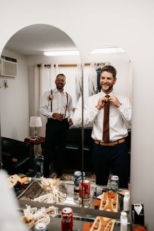 Two people getting ready in a dressing room with drinks and snacks on the counter.