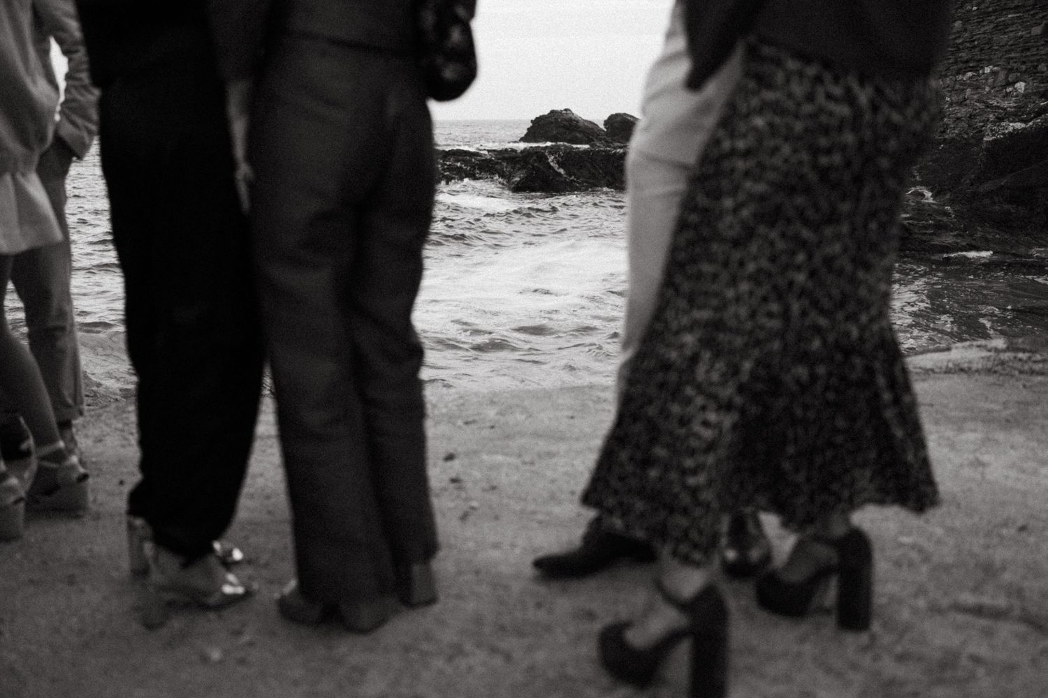 Black and white image of guests' legs and feet at a formal outdoor event.