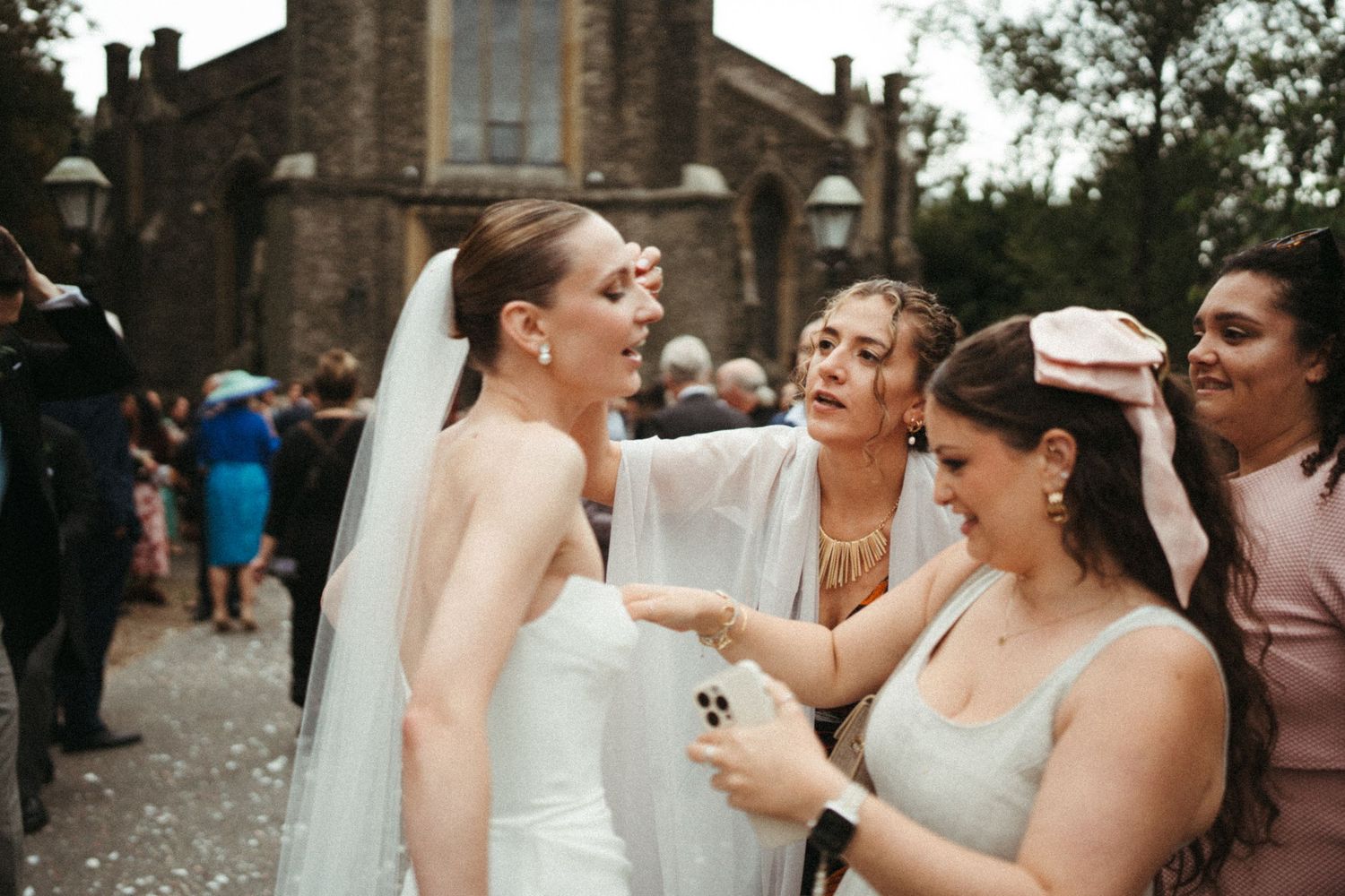Joyful wedding party shares laughter and drinks during outdoor celebration.