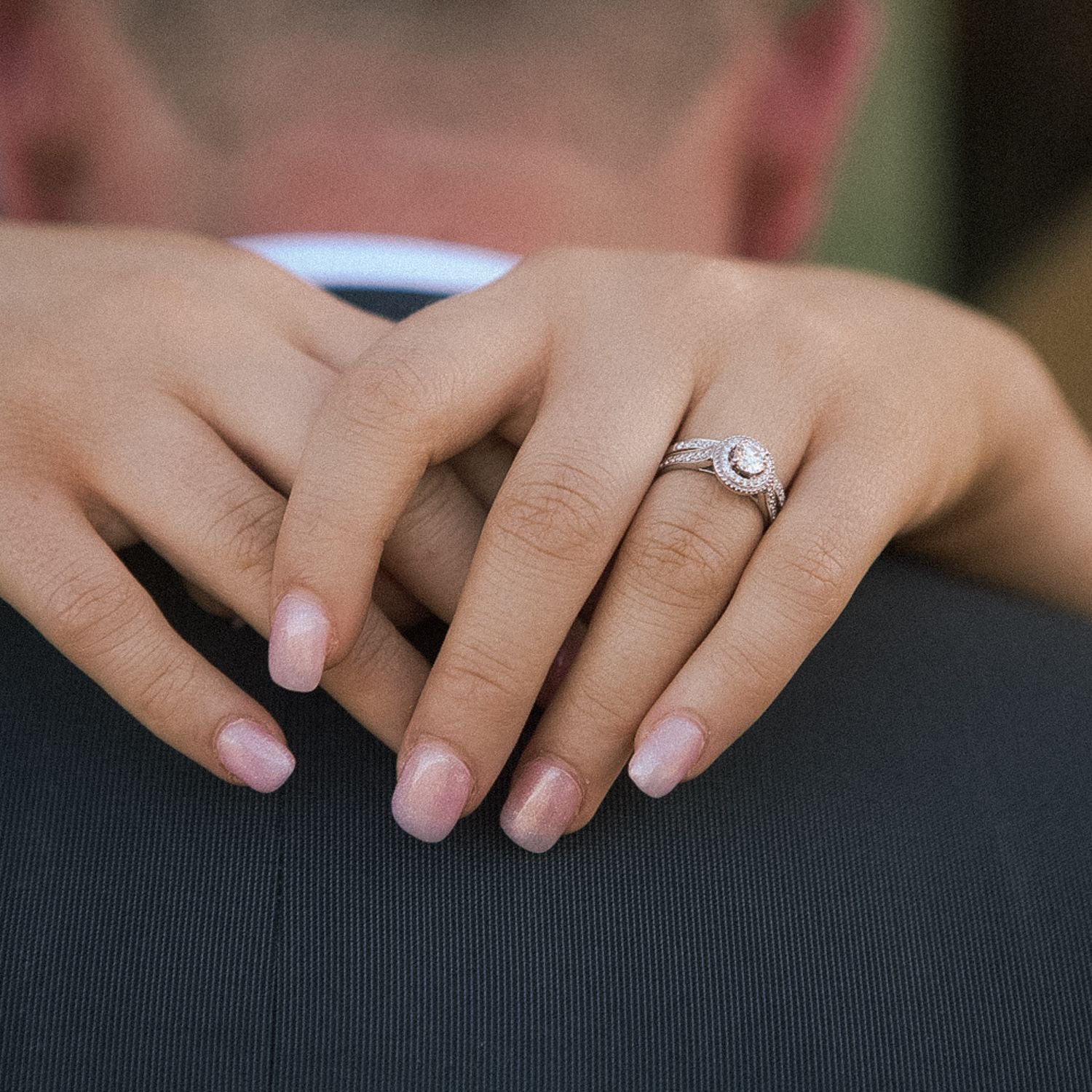 Bride's manicured hands and diamond ring wrapped around groom in suit jacket, Bury St Edmunds wedding.