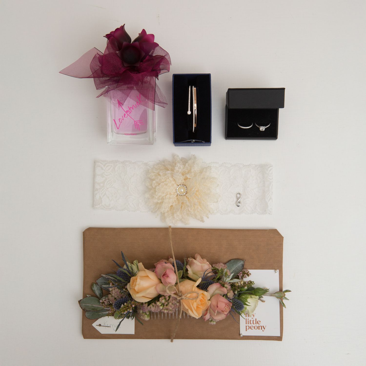 Bridal accessories layflat with perfume, wedding rings in box, lace garter, and flower comb, Bury St Edmunds wedding.