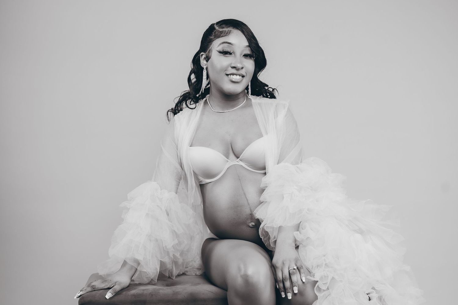 A glamorous boudoir photoshoot featuring white tulle and soft lighting in black and white.