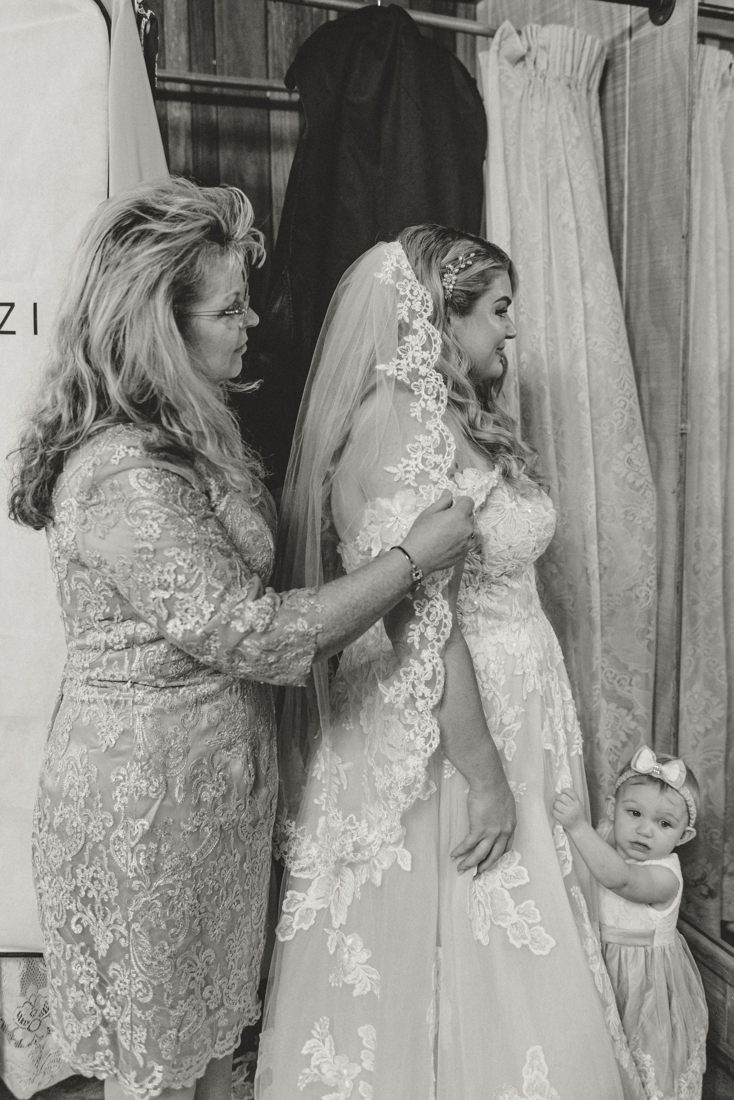 Bride's mother adjusting bride's veil and looking in a mirror.