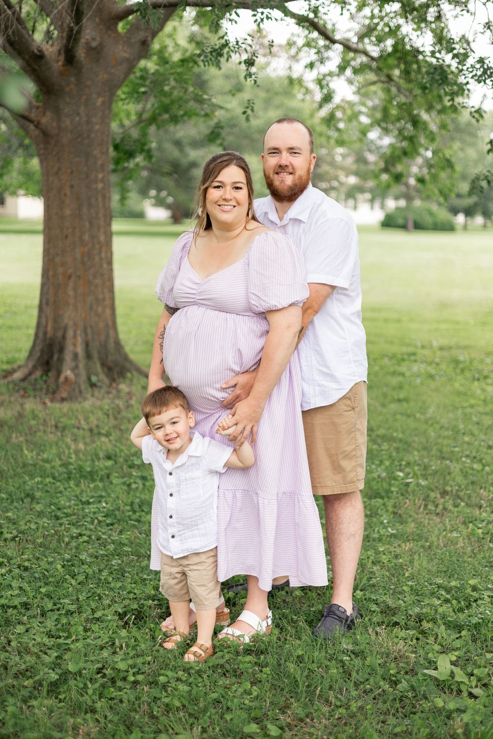 A family portrait under a large oak tree in a park setting.