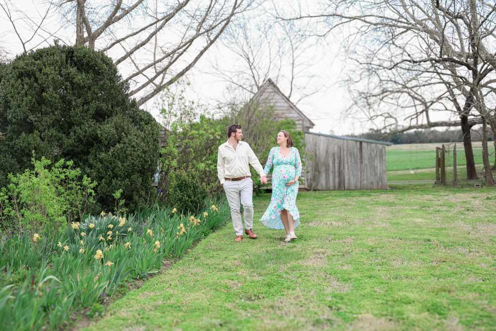 Spring maternity session in rustic field with daffodils and natural scenery.