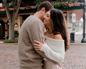 Happy couple embracing and laughing together in an outdoor urban setting on a sunny day.