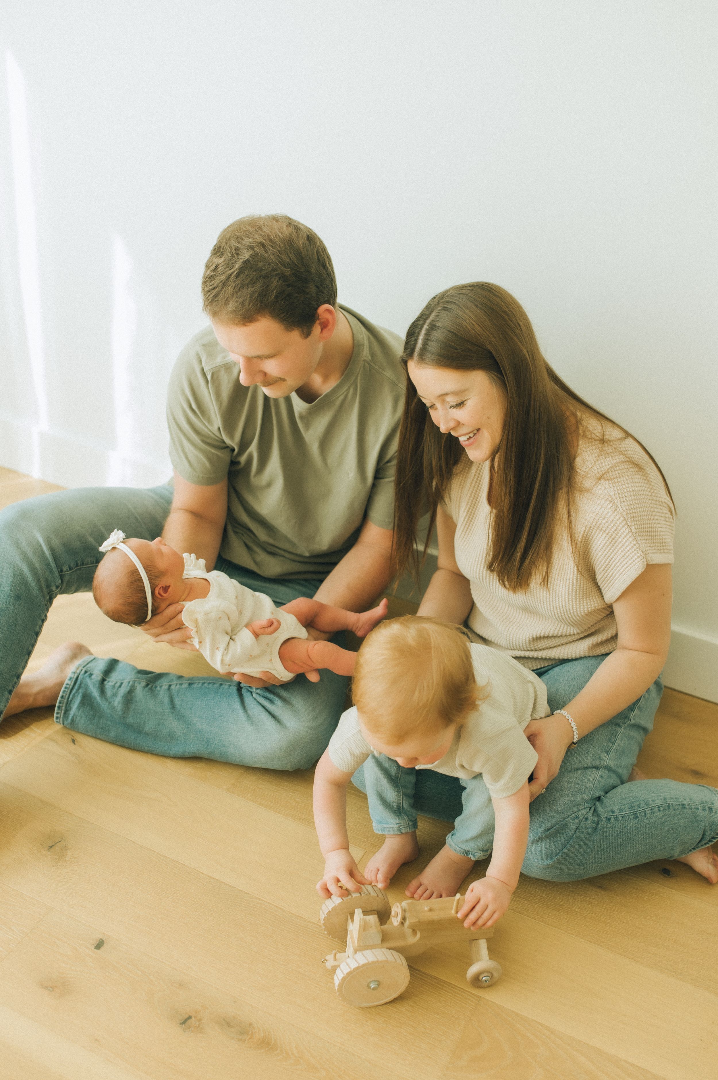 A tender family moment captured indoors as parents bond with their newborn baby.