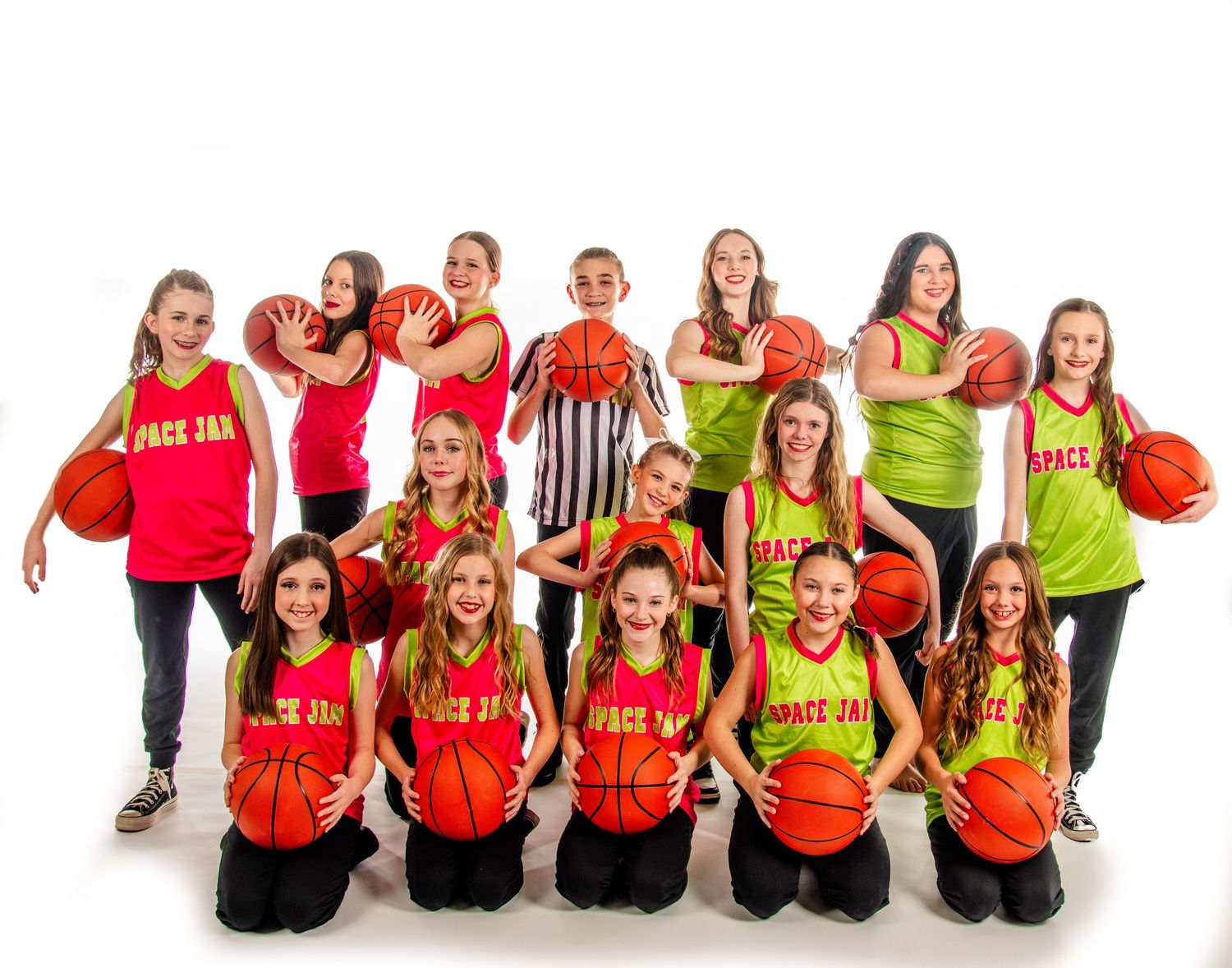 A youth basketball team poses together in bright red and yellow jerseys while holding orange basketballs on a white background.