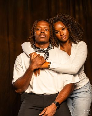 Intimate couple's portrait session against dark backdrop with warm lighting.