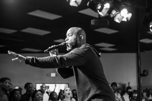 Black and white photo of performers on stage with microphones in dramatic lighting.