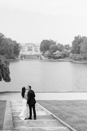 Black and white wedding photo sequence showing a romantic moment by a lake with a classical building in the background.