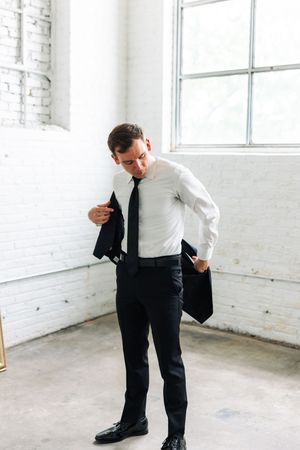 Series of photos showing person putting on formal black shoes and adjusting clothing in white room.