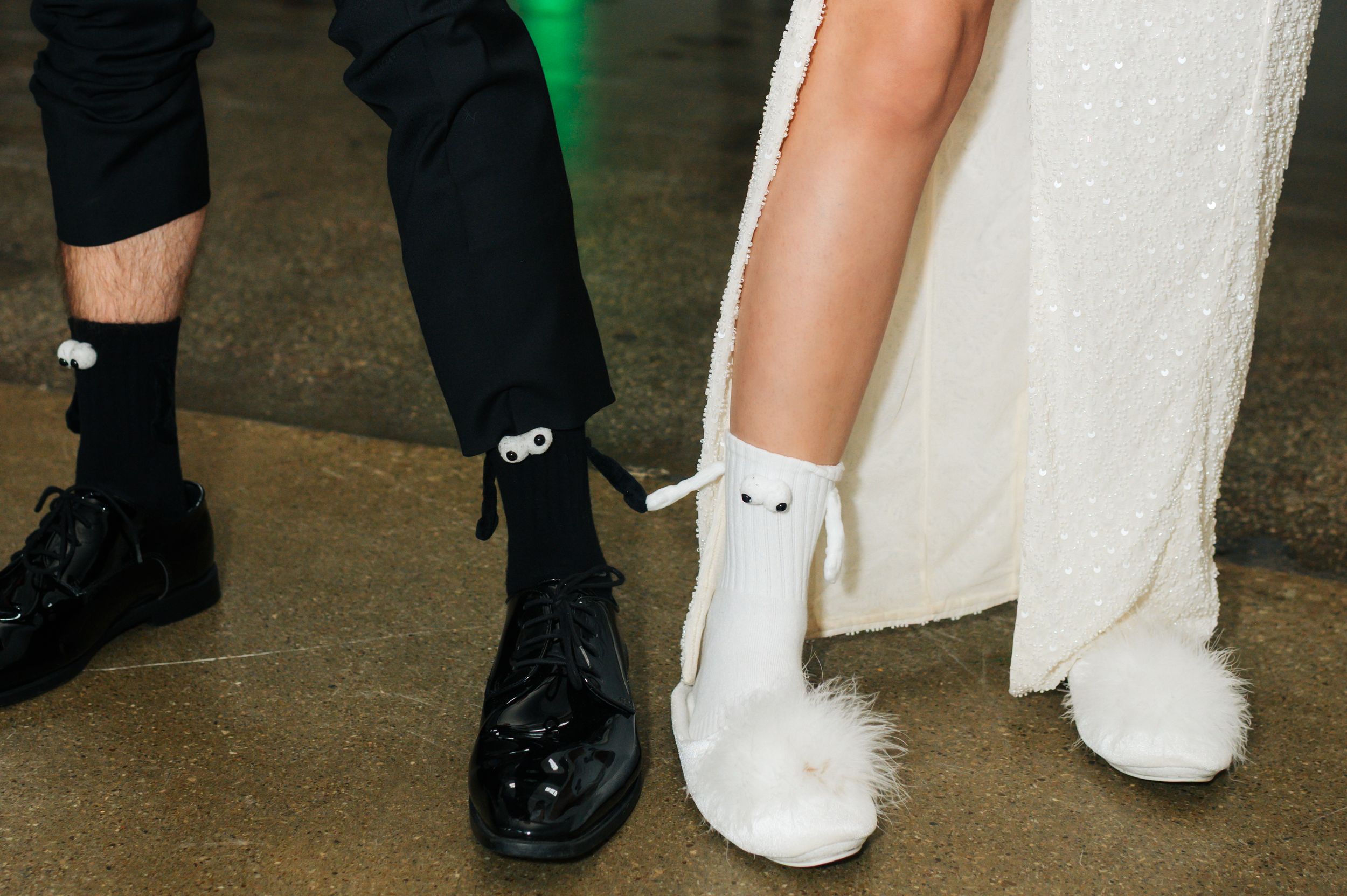 A pair of contrasting black and white formal shoes with matching socks worn under formal attire.