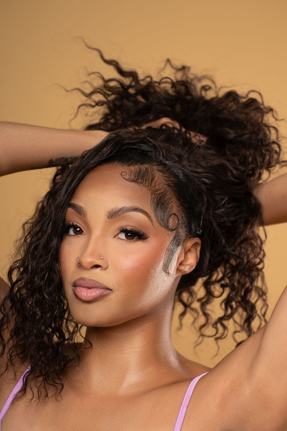 A beauty portrait series showing different angles of a model with curly dark hair wearing purple straps against a warm beige backdrop.
