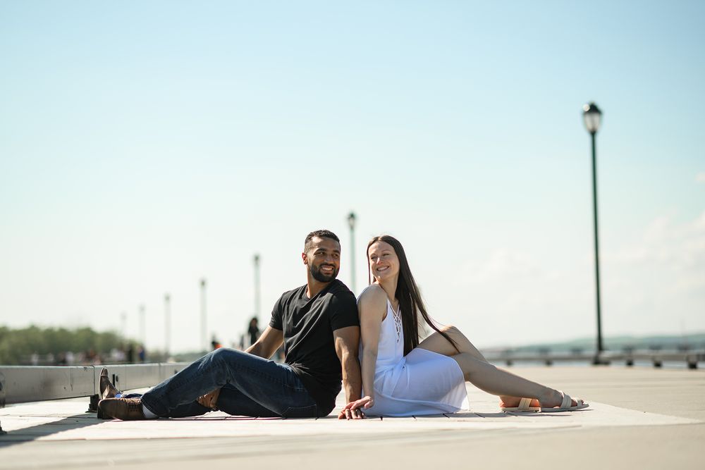 Two people relax and enjoy a sunny day while sitting on a modern rooftop terrace with city views in the background.
