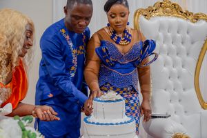 A couple in coordinating blue and brown traditional outfits share a sweet moment during their wedding celebration.