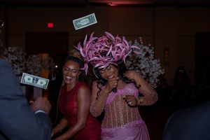 People dancing and celebrating at a party with money floating in the air and festive pink decorations.