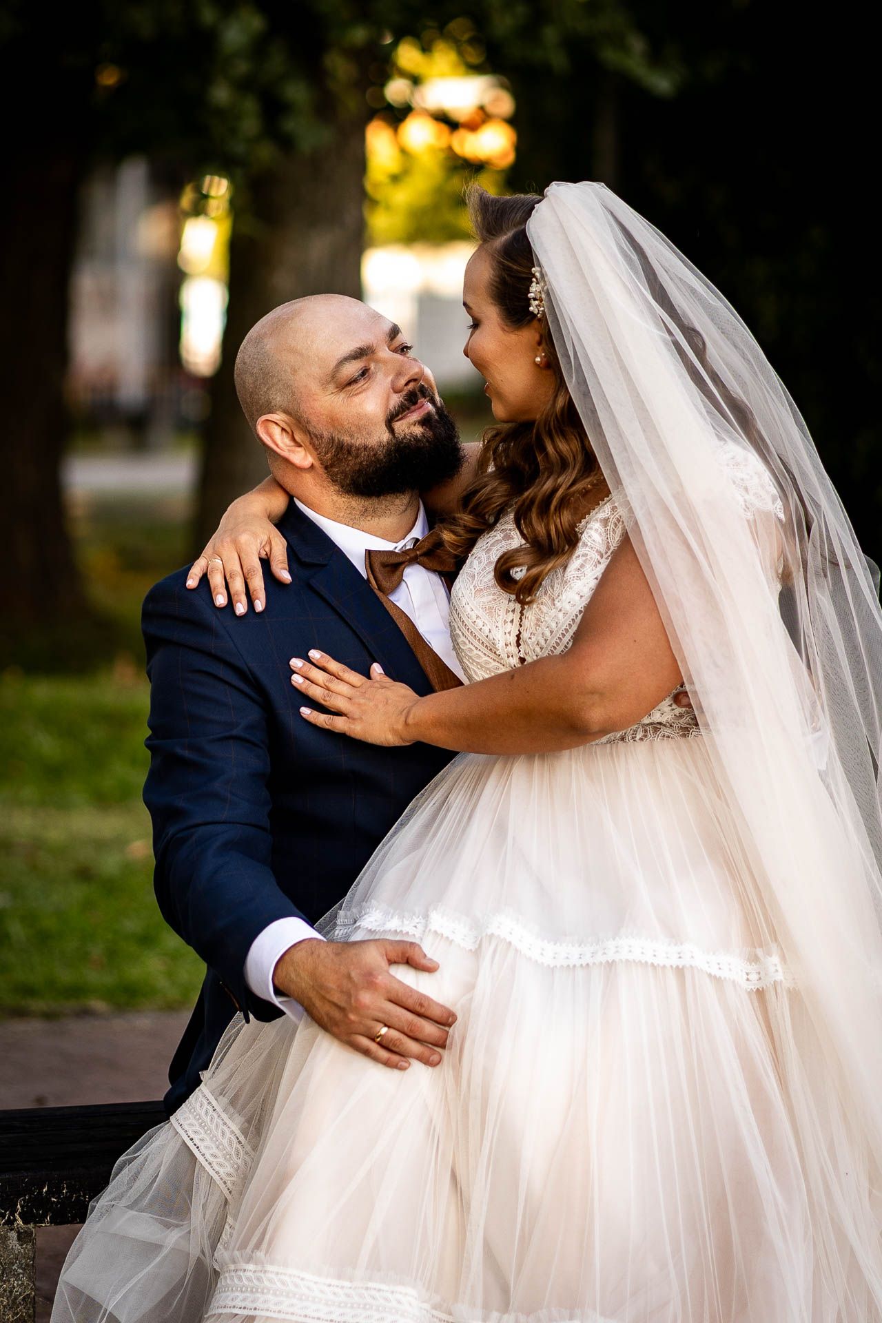 Wedding couple sharing intimate moments in a park during golden hour.