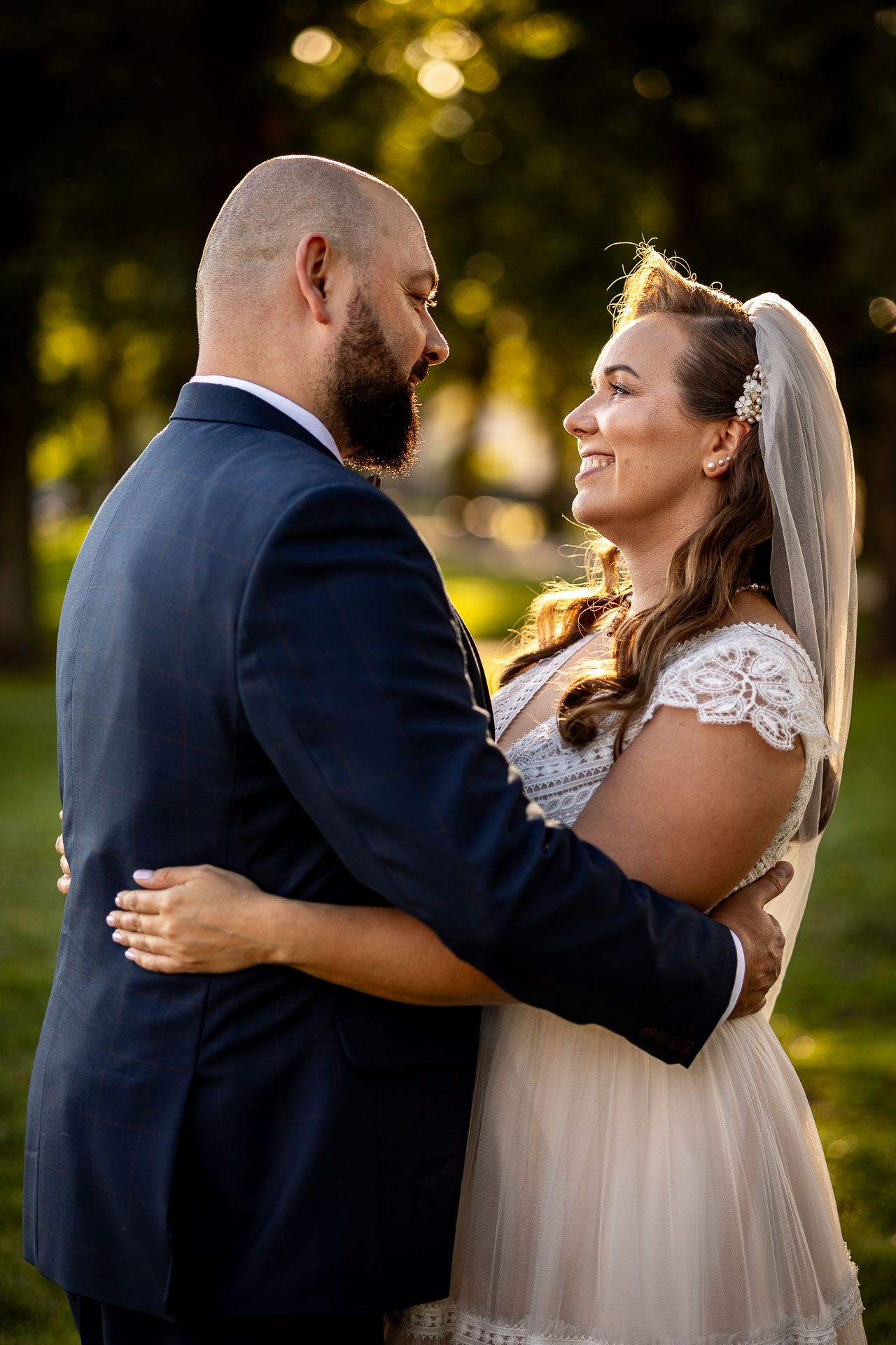 Joyful wedding couple embracing outdoors during golden hour photography session.