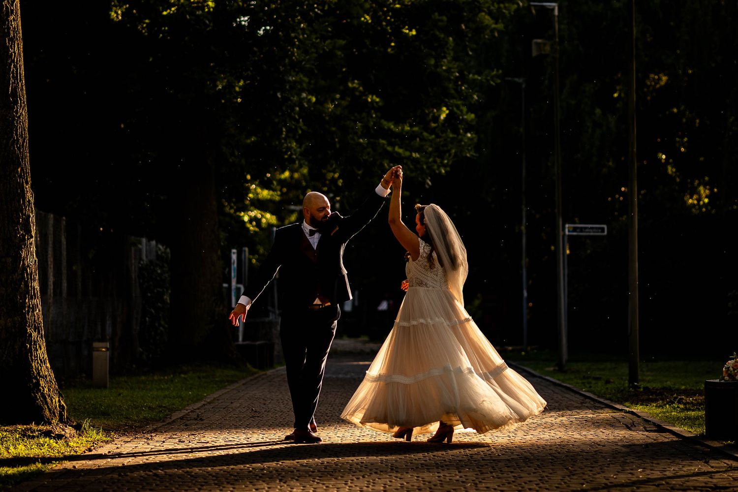 Silhouetted wedding couple walking together against a dramatic backlit forest backdrop.