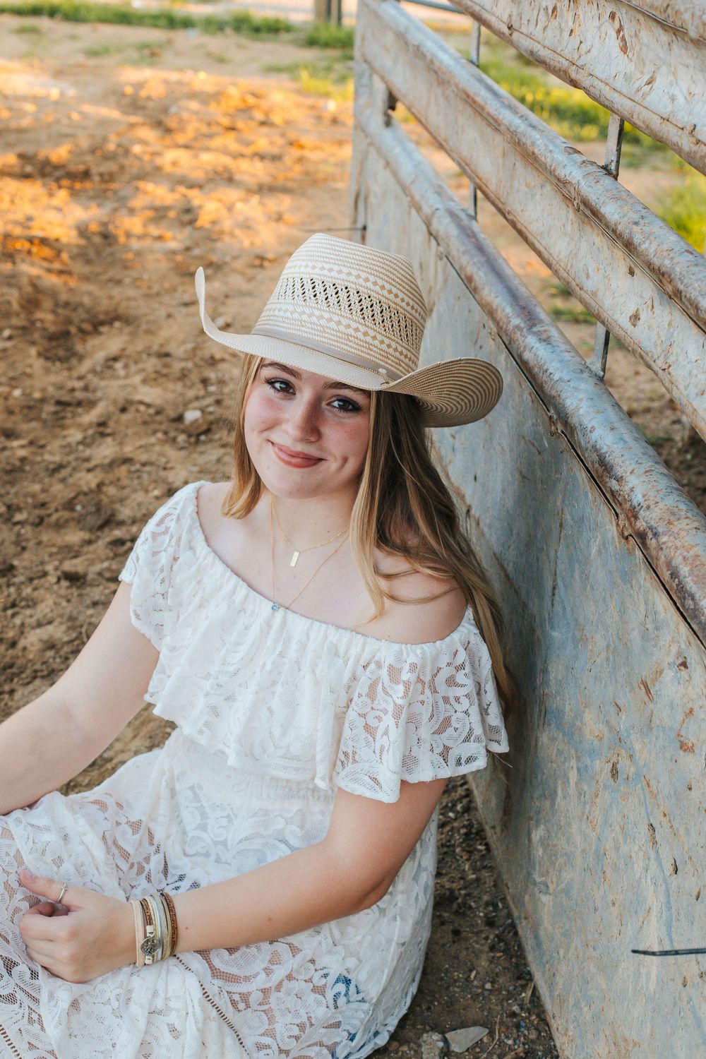 A series of outdoor portraits featuring someone in a white lace dress and straw hat sitting against a rustic wall.