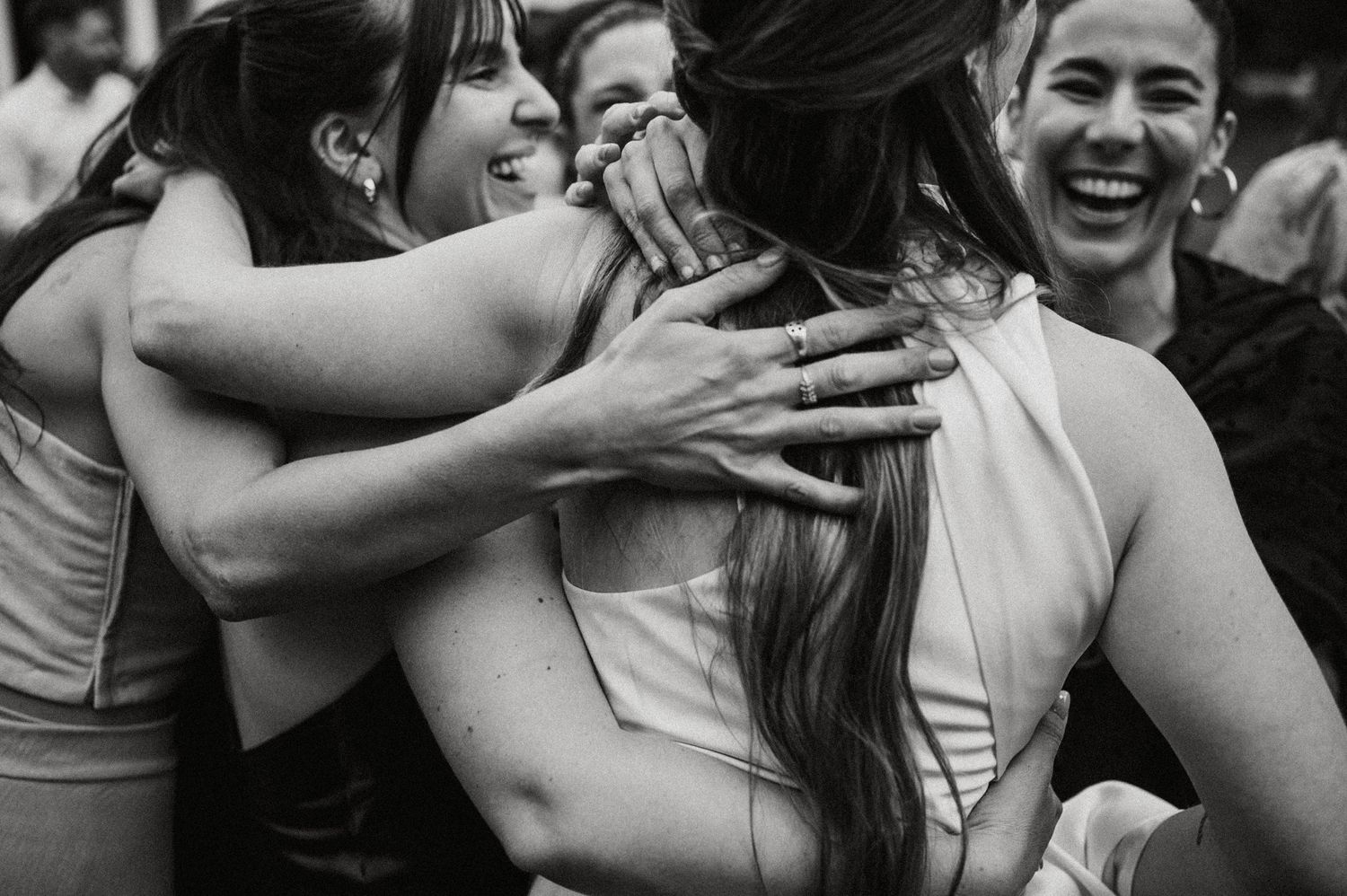 A black and white photo shows a group of people laughing and embracing during a joyful celebration moment.
