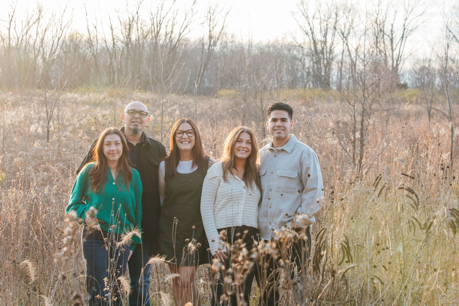 A group of people pose together in a field of tall grass during autumn.