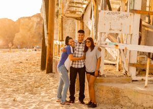 Three people stand together in the warm sunlight against a rustic wooden barn structure.