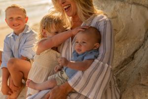 Family shares joyful moment together while sitting against coastal rock formation.