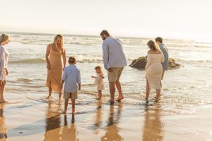 Group of people standing at ocean's edge during sunset beach gathering.