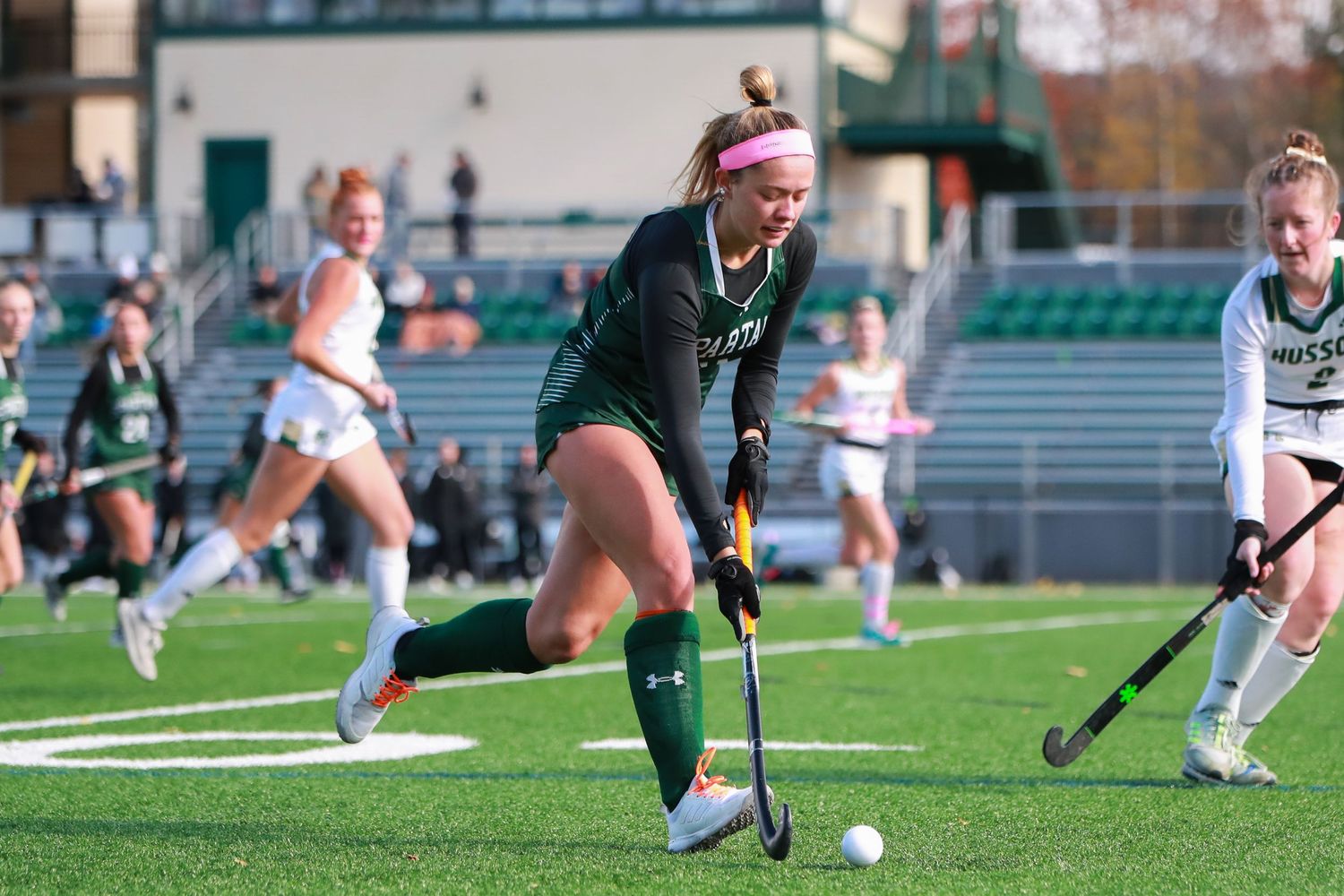 Field hockey players battle for possession during competitive match on artificial turf.