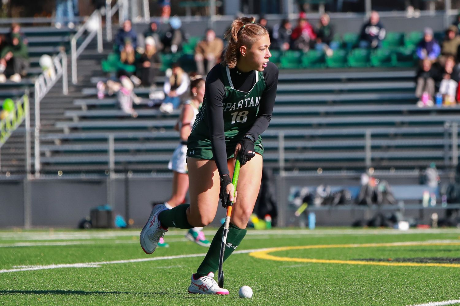 Athletes in green and white uniforms battle for possession during a competitive soccer match.