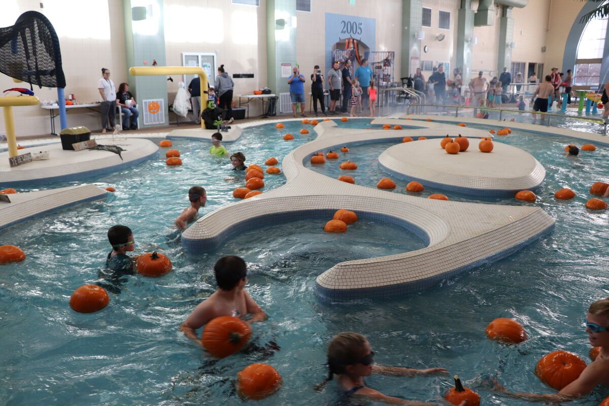 Children swimming amongst pumpkins inside a South Suburban rec center pool