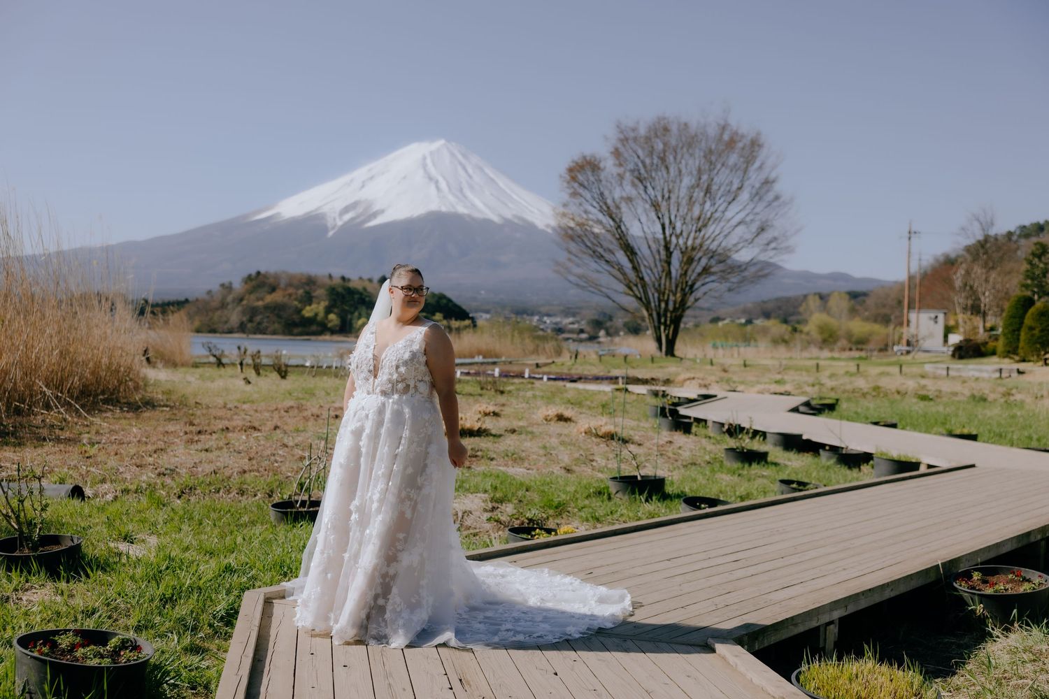 Wooden boardwalk stretches along Lake Yamanaka's shore with Mount Fuji rising majestically in the background.