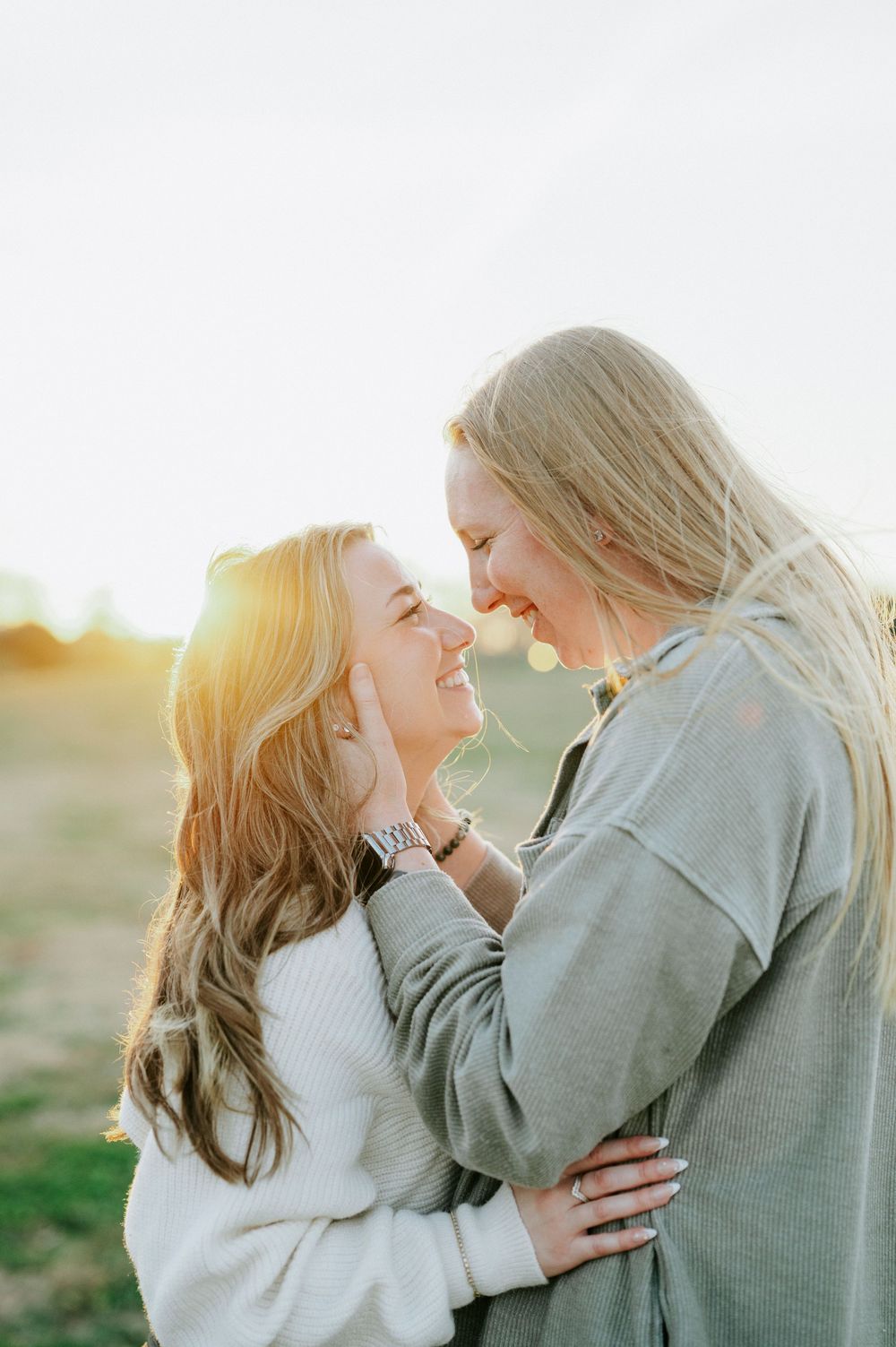 Two people share a tender moment in warm sunset light wearing coordinated casual outfits.
