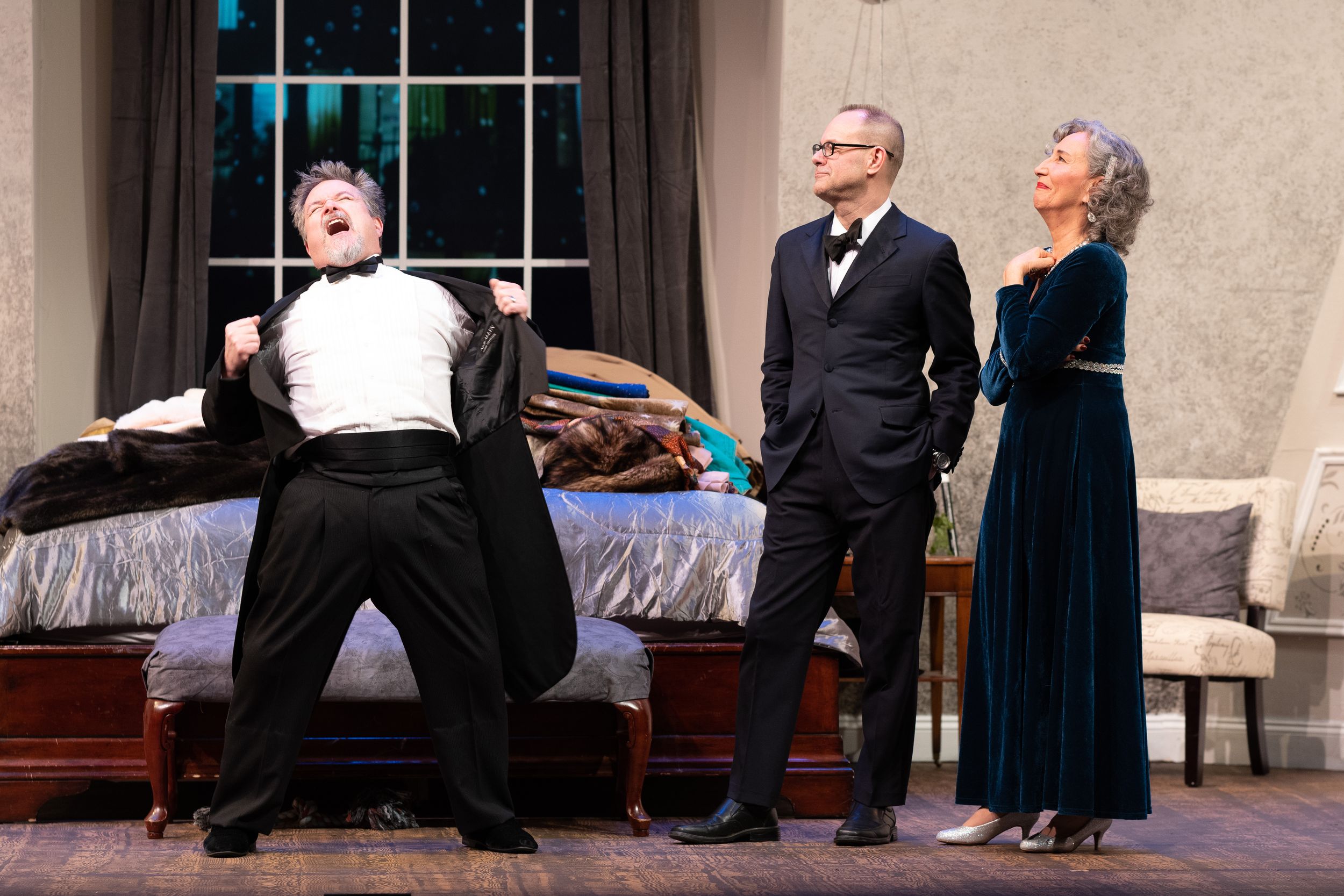 Theatrical performance scene on stage with actors in formal attire.