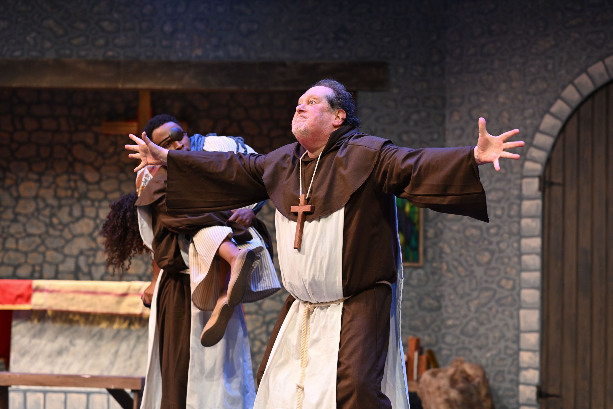 Medieval-themed stage performance with actors in brown robes and period costumes.