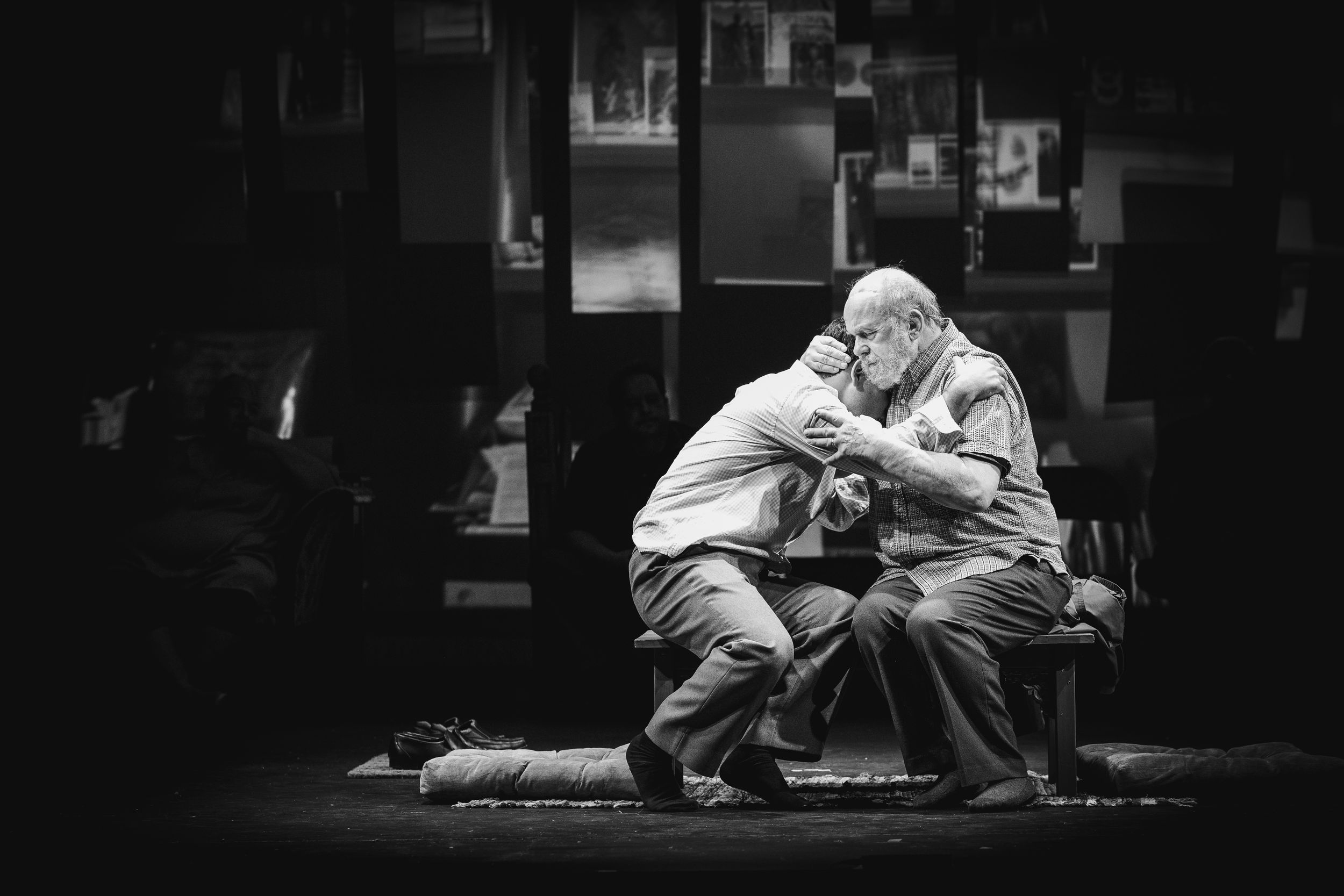 Black and white dramatic scene of performers in low lighting on stage.