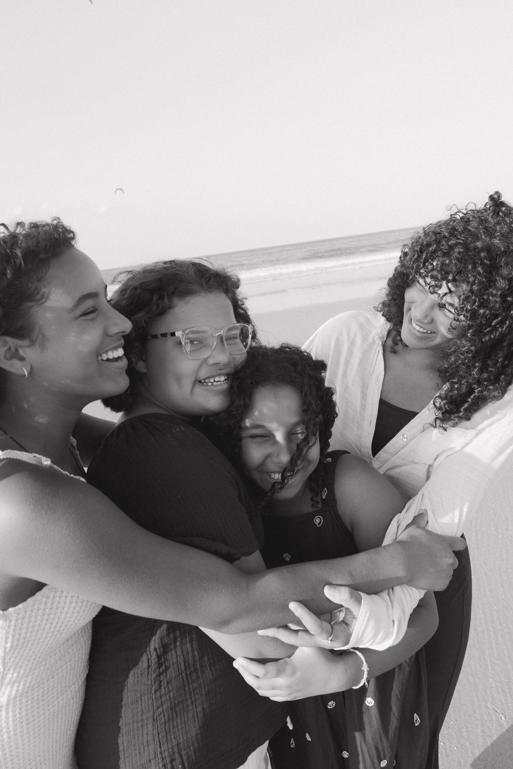 A series of four black and white photos showing joyful embraces and laughter between friends.