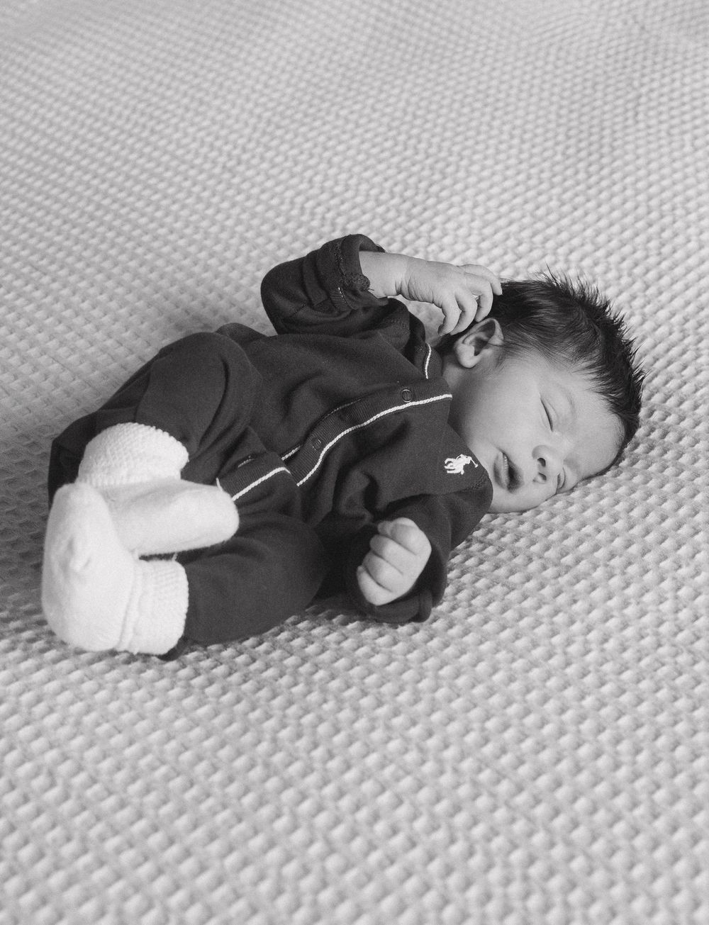 Black and white series showing a baby lying on a textured surface in various sleeping positions.