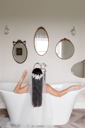 A series of minimalist bathroom photos showing a white freestanding bathtub with vintage mirrors on a neutral wall.